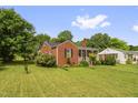 Quaint brick home with a covered front porch, showcasing a well-kept lawn and mature trees in a serene setting at 625 Columbia Ave, Burlington, NC 27217
