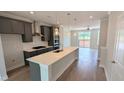 Contemporary kitchen featuring gray cabinetry, stainless appliances, an island with quartz countertops, and hardwood flooring at 691 Bandon Aly, Cary, NC 27513