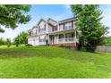 View of the side of this two-story home with a front porch and a well-manicured lawn and mature trees at 75 Mountainside Ln, Sanford, NC 27332