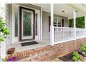 Covered front porch with white railings, brick steps, decorative glass front door and purple hydrangeas at 75 Mountainside Ln, Sanford, NC 27332