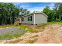 View of a home featuring gray siding, brick foundation, and lush green surroundings at 150 Will Woods Way, Franklinton, NC 27525