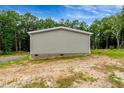 Rear view of home with gray siding, brick foundation, surrounded by green landscape and trees at 150 Will Woods Way, Franklinton, NC 27525