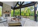 Inviting covered patio with stone fireplace, comfortable seating, and views of wooded yard at 15517 Possum Track Rd, Raleigh, NC 27614