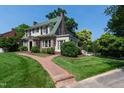 Landscaped exterior showcasing a brick walkway and pristine lawn leading to this gorgeous home at 1700 St Marys St, Raleigh, NC 27608