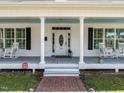 Inviting front porch with classic columns, rocking chairs, and a charming brick walkway at 212 W Church St, Benson, NC 27504