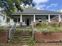 Bungalow with brick foundation, overgrown yard and stairs leading to a covered front porch with columns at 431 Charles St, Henderson, NC 27536