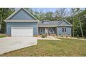 Inviting blue home featuring a garage, cozy front porch with chairs, and well-maintained lawn at 5550 Mountain Trl, Snow Camp, NC 27349