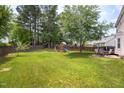 Spacious backyard with a large grassy area, wooden fence, and a fun playset for children to enjoy at 6924 Coventry Ridge Rd, Raleigh, NC 27616