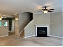 Open-concept living room with fireplace, ceiling fan, and staircase at 7331 Bonnie Ridge Ct, Raleigh, NC 27615