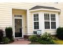 Welcoming front entrance featuring a decorative window, adjacent garden, and brick-paved path to the door at 100 Sheraton Ln, Garner, NC 27529