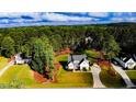 An aerial view shows a white two-story home nestled among trees with a long driveway and landscaping at 104 Crosby Ln, Sanford, NC 27330