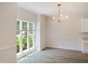 Bright dining room featuring wood-look floors, wainscoting, a modern chandelier, and a window overlooking the yard at 137 Wintermist Dr, Cary, NC 27513