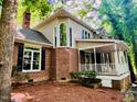 Charming brick home featuring a covered porch, large windows, and lush landscaping offering a serene and inviting outdoor space at 1512 Cumberland Rd, Chapel Hill, NC 27514