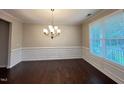 Bright dining room with hardwood floors, wainscoting, and elegant chandelier lighting at 1746 Hammocks Beach Trl, Apex, NC 27502
