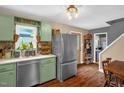 Well-maintained kitchen with painted cabinets, stainless steel refrigerator, and hardwood floors at 1869 Brevard Rd, Graham, NC 27253