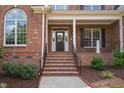 Charming front porch with brick steps, columns, and a black front door at 209 Bailey Ridge Dr, Morrisville, NC 27560