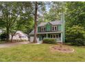 Two-story green home featuring a well-maintained front yard and a detached white garage in the background at 2724 Glastonbury Rd, Apex, NC 27539