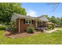 Well-kept brick home showcasing manicured landscaping and a cozy front porch with attractive black railings at 305 Oakgrove Dr, Graham, NC 27253