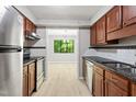 Galley kitchen with wood cabinetry, stainless steel appliances, and view into living area at 3088 Colony Rd # A, Durham, NC 27705