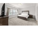 Serene main bedroom with a tray ceiling, large window, and plush carpeting at 409 Rhamkatte Rd, Holly Springs, NC 27540