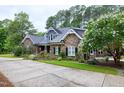 Charming stone house boasts a spacious driveway, lush lawn, and blooming tree at 4924 Stoneyoak Ln, Raleigh, NC 27610
