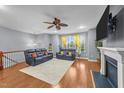 Spacious living room with hardwood floors, ceiling fan, fireplace, and staircase at 5321 Cambridgeshire Loop, Cary, NC 27519