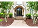 Elegant entryway with an ornate black front door, brick steps, and mature landscaping at 6005 Carlyle Dr, Raleigh, NC 27614