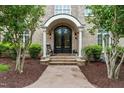 Elegant brick home featuring a stunning arched entryway, ornate double doors, and meticulously landscaped surroundings at 6005 Carlyle Dr, Raleigh, NC 27614