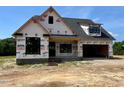 New construction featuring a brick base and a modern, open garage at 6332 River Rd, Fuquay Varina, NC 27526