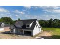 Elegant white home featuring dark window frames and roof situated on a spacious lot surrounded by lush greenery at 6332 River Rd, Fuquay Varina, NC 27526