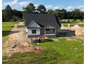New home in a picturesque setting, featuring dark roof, and open porch on a large lot with scattered trees at 6332 River Rd, Fuquay Varina, NC 27526