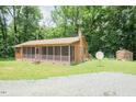 Ranch home with screen porch and storage building, set amongst mature trees and a gravel drive at 7030 Stockard Rd, Snow Camp, NC 27349