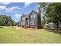 Charming blue two-story home boasts a landscaped front yard, brick chimney, and inviting entrance at 104 Goldleaf Ct, Angier, NC 27501