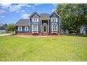 Charming blue two-story home boasts a landscaped front yard, brick foundation, and inviting entrance at 104 Goldleaf Ct, Angier, NC 27501