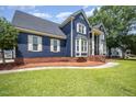 Charming blue two-story home boasts a landscaped front yard, brick foundation, and inviting entrance at 104 Goldleaf Ct, Angier, NC 27501