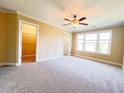 Bedroom with a ceiling fan, neutral carpet, and an open walk-in closet for ample storage at 115 Ballyliffen Ln, Cary, NC 27519