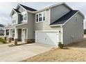 Charming two-story home featuring an attached two-car garage, a covered front porch, and a well-maintained lawn at 13 Knotty Pine Lane, Clayton, NC 27520