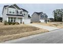 Charming two-story home with gray siding, a front porch, and a driveway leading to the garage at 13 Knotty Pine Lane, Clayton, NC 27520