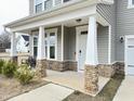 Inviting front porch with stylish stone pillars and comfortable seating, perfect for relaxing outdoors at 13 Knotty Pine Lane, Clayton, NC 27520