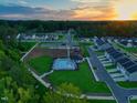 Aerial view shows community pool, playground, and well-maintained lawns at sunset at 384 Chesapeake Commons St # 128, Garner, NC 27529