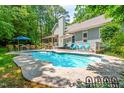 Backyard view of a pool with seating and the rear of a house on a sunny day at 7401 Heartland Dr, Wake Forest, NC 27587