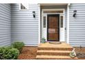 Close-up of the home's entryway featuring a wood door, brick steps, and decorative lighting at 7605 Sandy Lake Ct, Raleigh, NC 27613