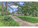 Charming gray two-story house with red front door has a long driveway, lush landscaping, and mature trees at 8121 Bentwood Pl, Raleigh, NC 27615