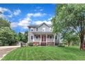 Charming two-story home features a well-manicured lawn, mature trees, and classic architecture with a red front door at 8121 Bentwood Pl, Raleigh, NC 27615