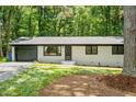 Charming single-story home with a painted brick exterior, complemented by a black garage door at 104 Woodcrest Dr, Chapel Hill, NC 27516