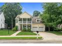 Charming yellow two-story home with double front porch, well-manicured lawn and a two-car garage at 10415 Ashmead Ln, Raleigh, NC 27614