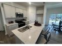 Bright kitchen featuring a quartz countertop island with sink, stainless steel appliances, and eat in dining area at 11198 Salers Loop, Middlesex, NC 27557