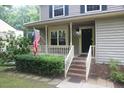Inviting front porch with brick steps, lush hedges, and an American flag at 116 Trinity Woods Dr, Raleigh, NC 27607