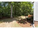 Lush backyard with mature trees, mulch beds, and a wooden deck, providing a serene outdoor space at 1210 Eastham Dr, Apex, NC 27502