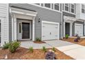 Close-up of a townhome featuring a black front door and a white garage door with modern design at 127 Central Townes Way # 303, Raleigh, NC 27603